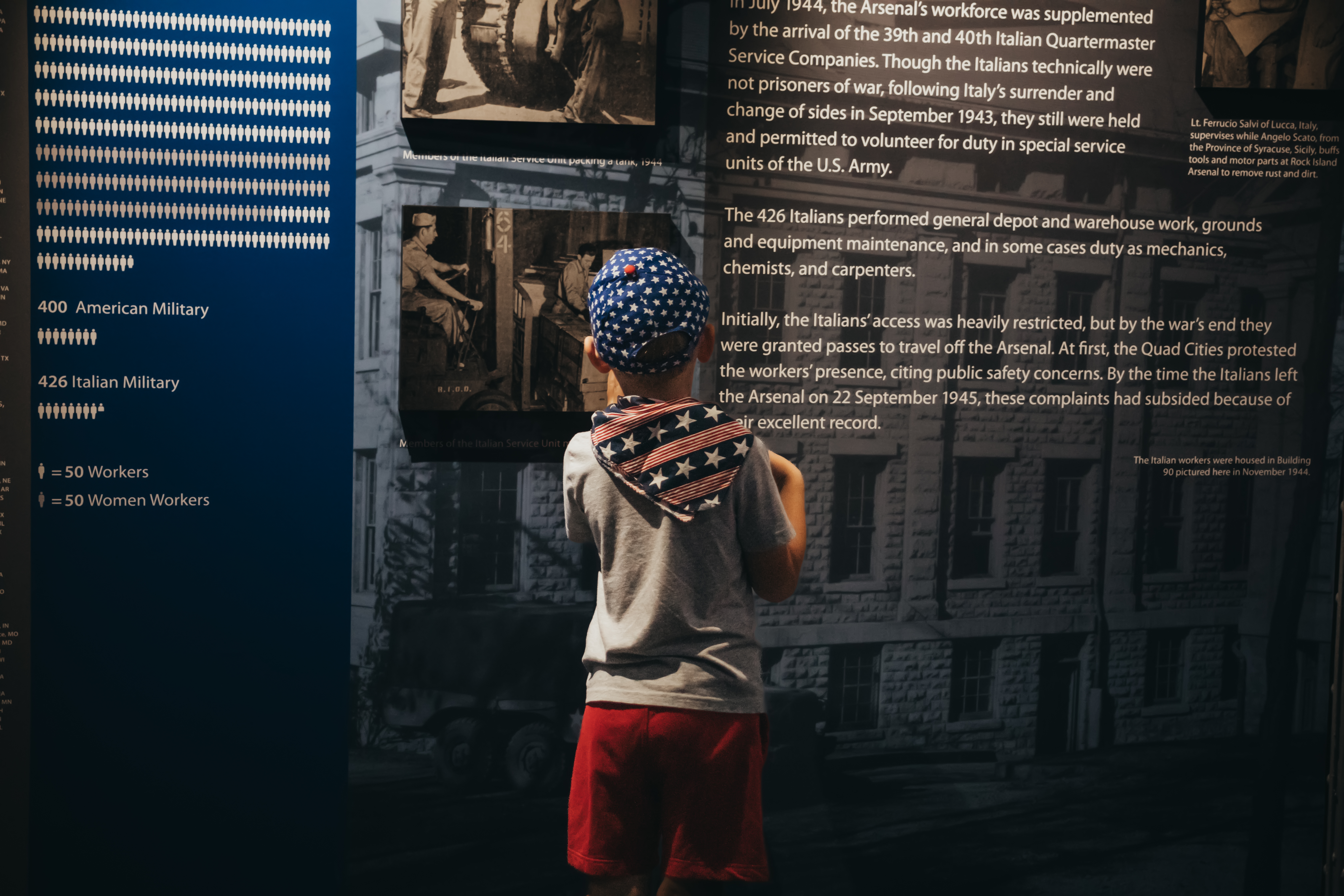 A child with American apparel reading from a musuem exhibit.